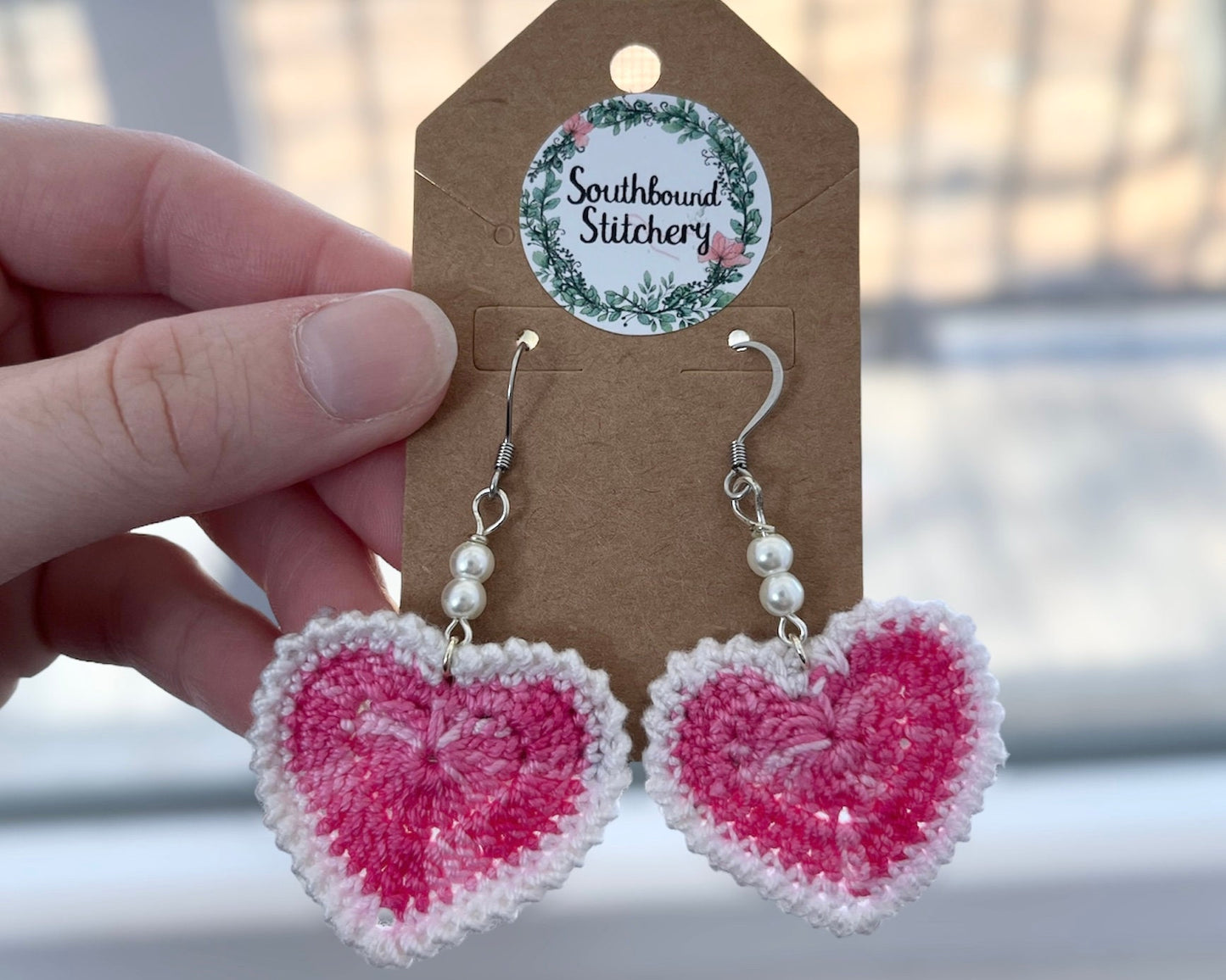 Heart-shaped earrings with pink and white color scheme on a Southbound Stitchery branded card.