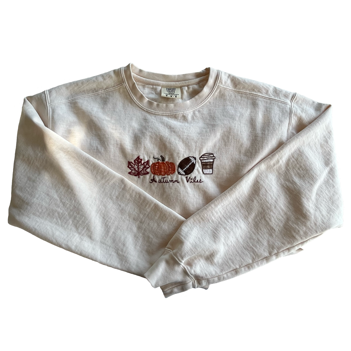 Folded white sweatshirt with autumn-themed design on a white background