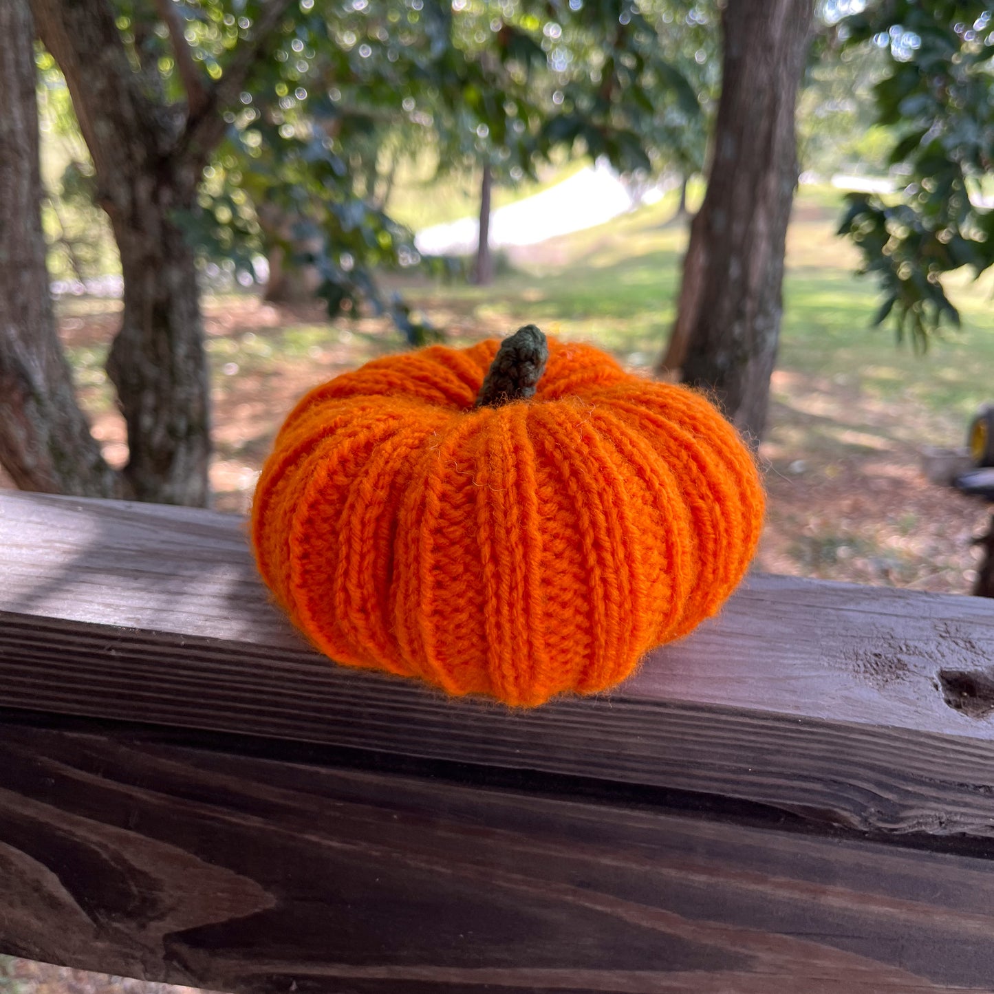 Knitted orange pumpkin on a wooden surface with a natural background