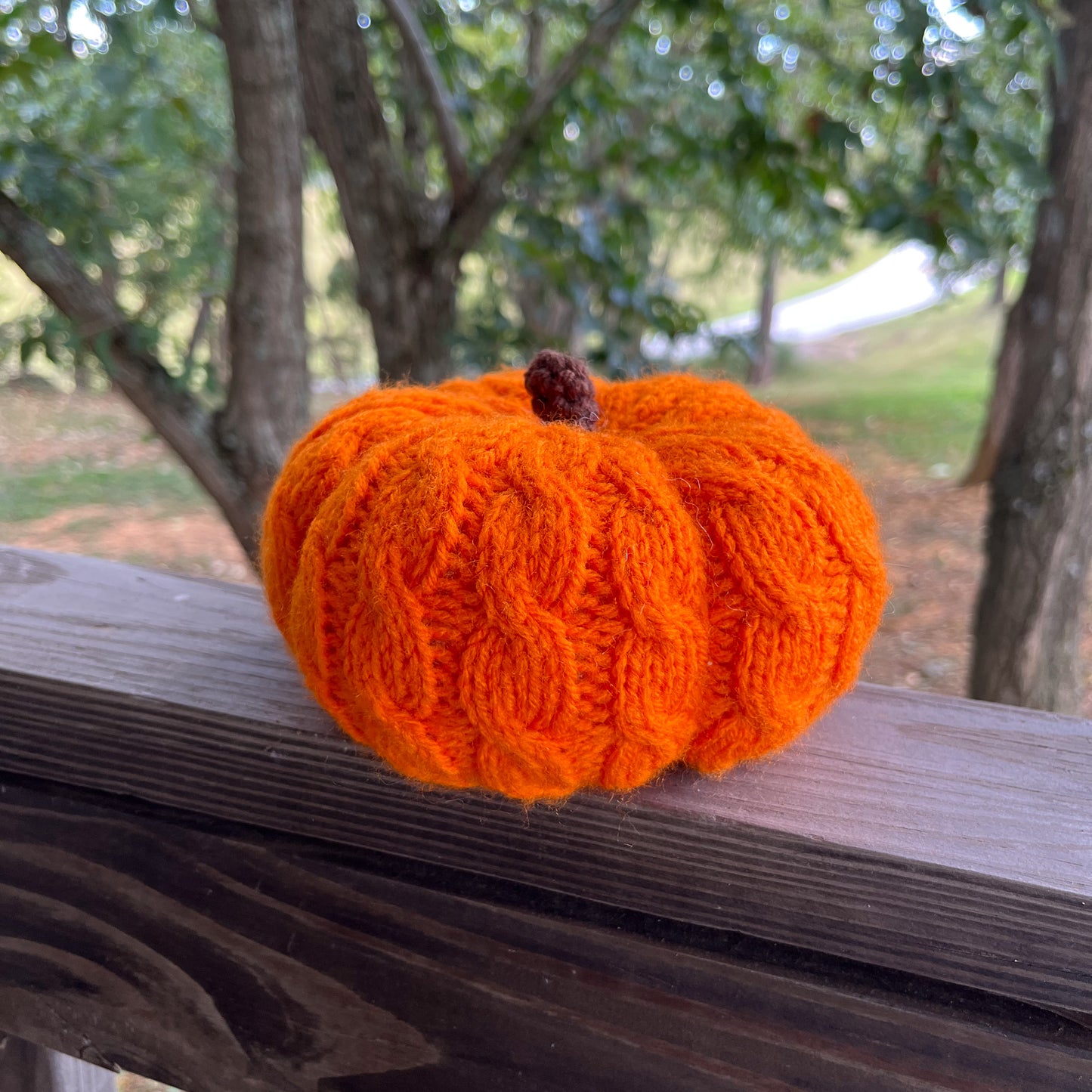 Knitted orange pumpkin on a wooden surface with a natural background