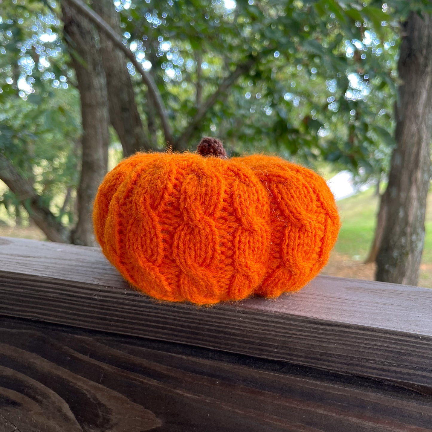 Knitted orange pumpkin on a wooden surface with a natural background