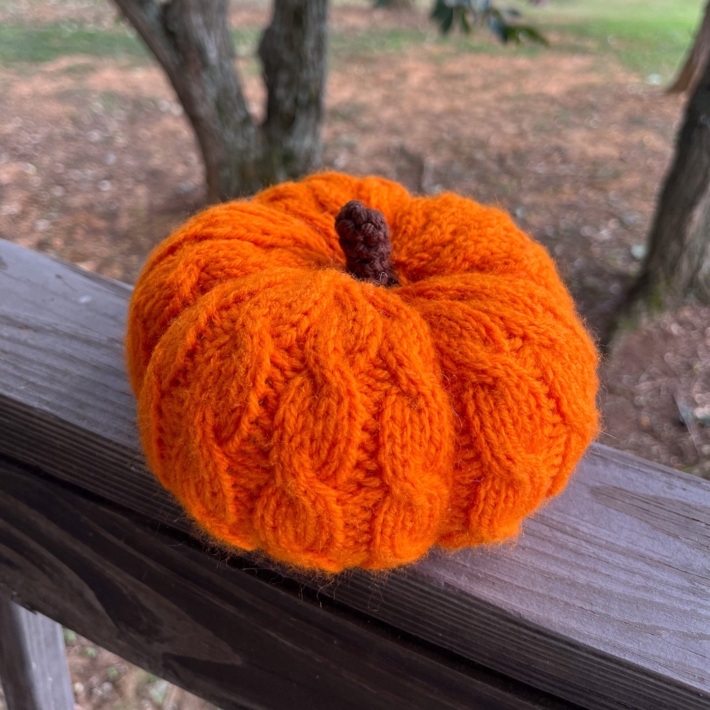 Knitted orange pumpkin on a wooden surface with a natural background