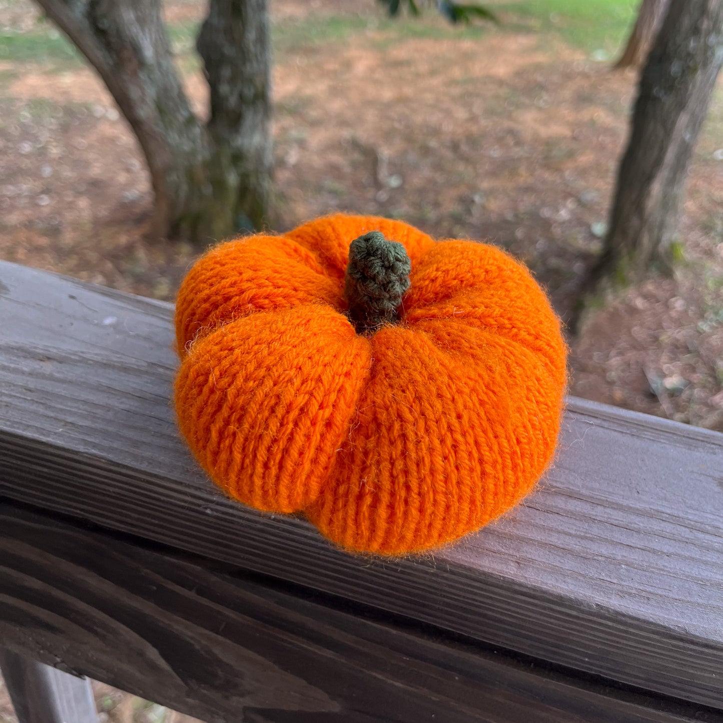 Knitted orange pumpkin on a wooden surface with a natural background