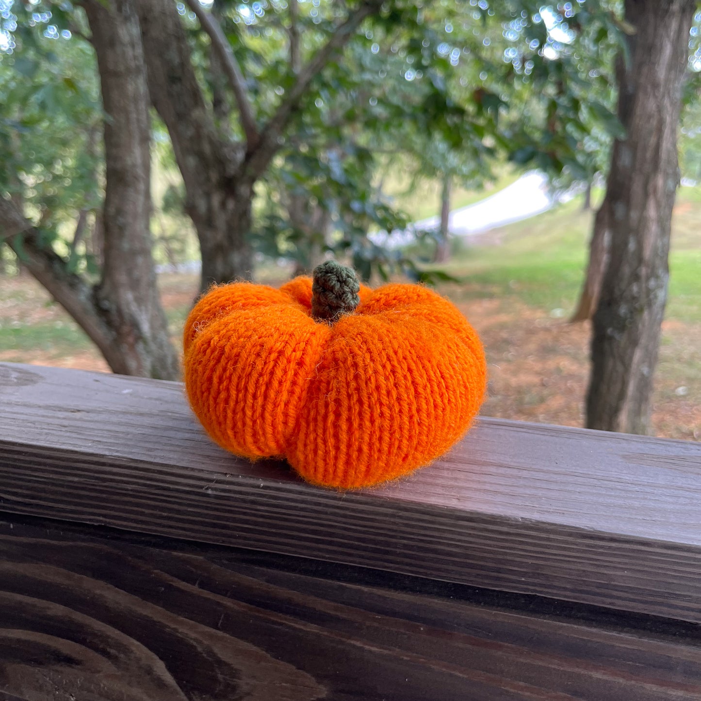 Knitted orange pumpkin on a wooden surface with a natural background