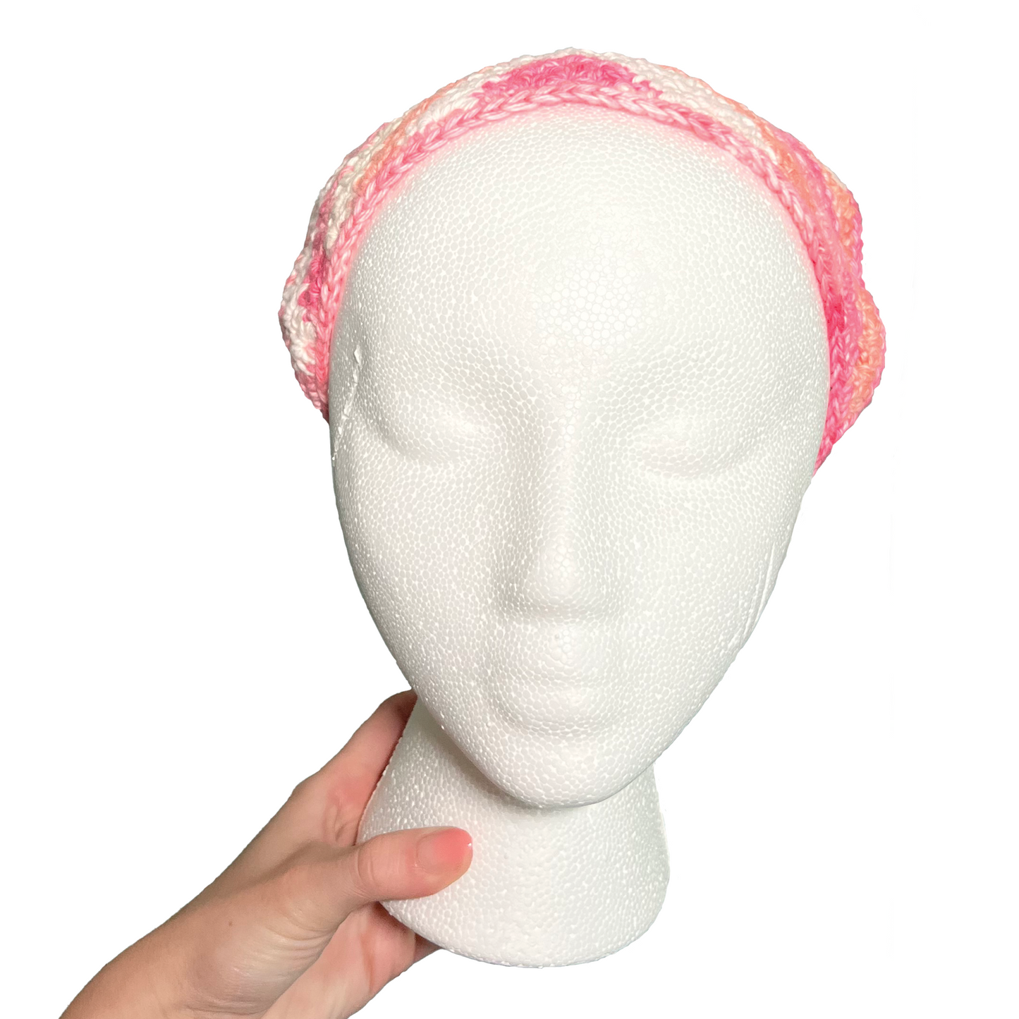 Mannequin head with a pink crocheted bandana on a white background