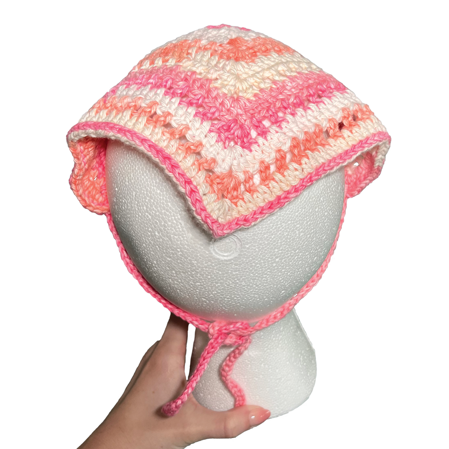 Crocheted bandana with pink and white pattern on a mannequin head.