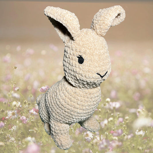 Crocheted bunny toy in a field of flowers