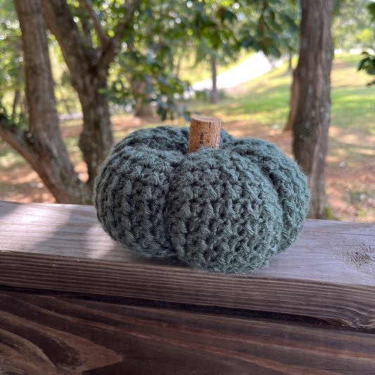Green crocheted pumpkin on a wooden ledge outside