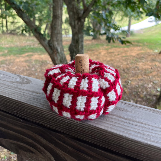 Red and white crochet pumpkin on wooden ledge outside