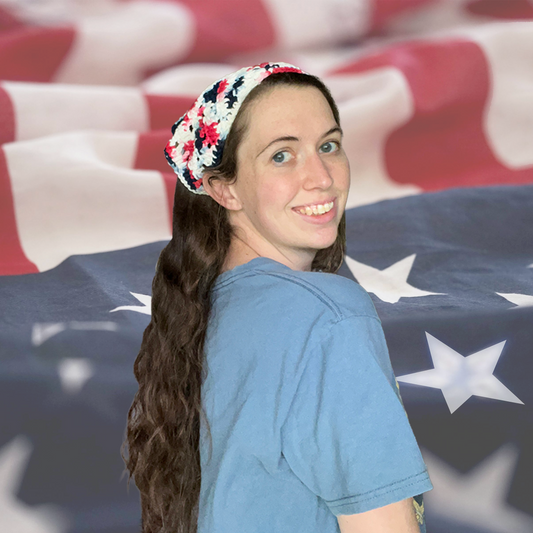 Woman with a red white and blue crochet bandana standing in front of an American flag